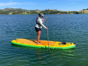 Paddle boarder in Black Hills Lake with Black Hills Bicycles and Boats rentals.