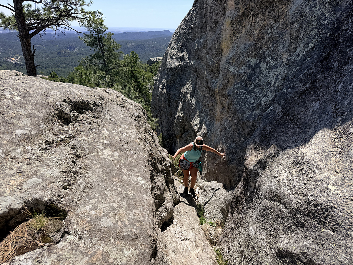 Woman climbing rock scramble on Mount Baldy Trail near Keystone, SD