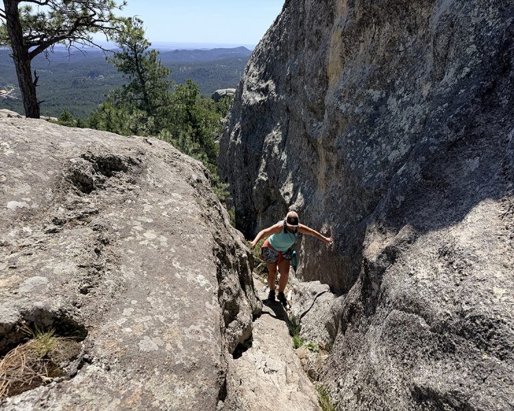 Woman climbing rock scramble on Mount Baldy Trail near Keystone, SD