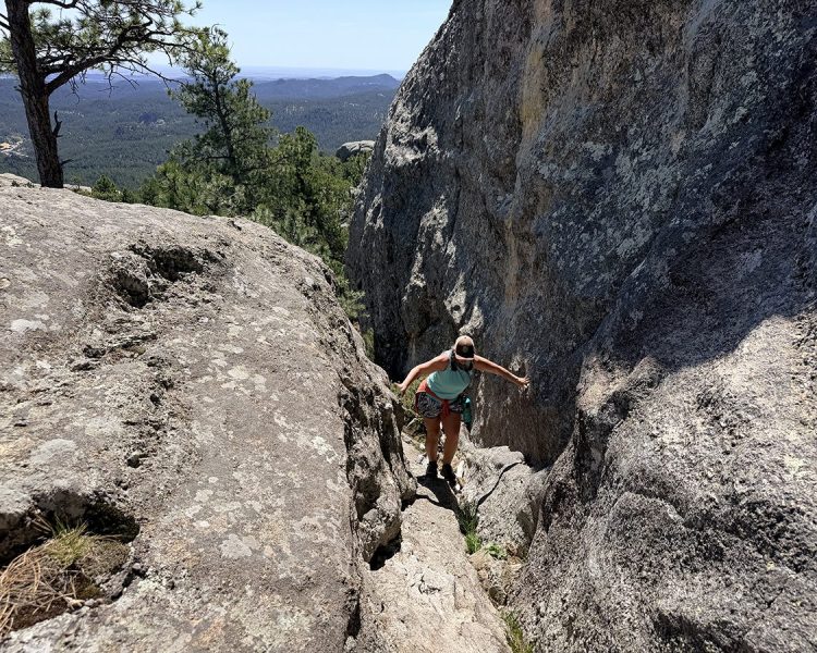 Woman climbing rock scramble on Mount Baldy Trail near Keystone, SD